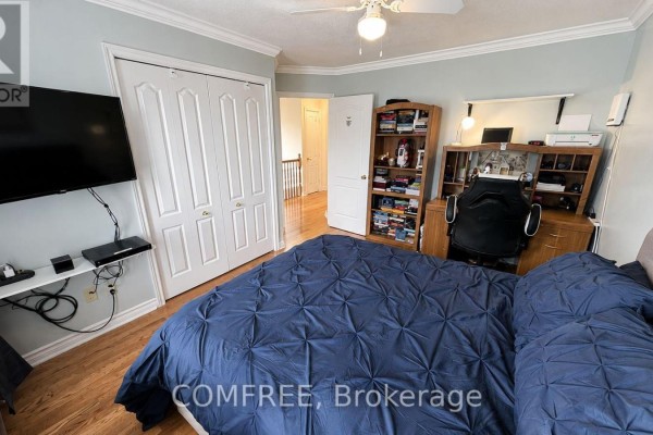 Bedroom with blue duvet, wall-mounted TV, desk, and bookshelf - 1960 Rolling Brook Drive Ottawa