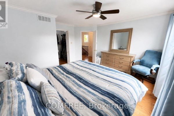 Bedroom with striped comforter, dresser, and blue armchair - 1960 Rolling Brook Drive Ottawa