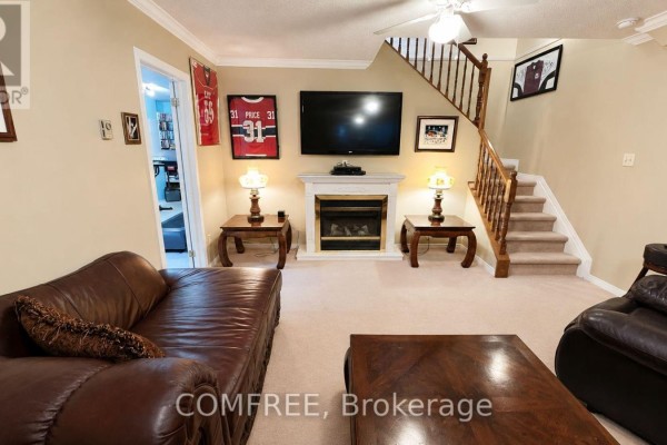 Living room with fireplace, TV, leather sofa, and hockey jerseys - 1960 Rolling Brook Drive Ottawa