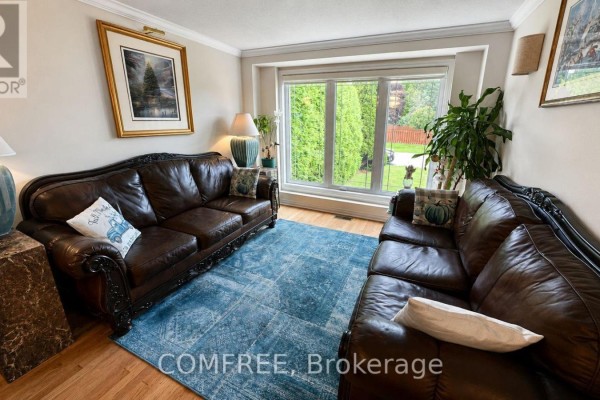 Living room with two brown leather sofas, a blue patterned rug, and a large window.  - 1960 Rolling Brook Drive, Ottawa