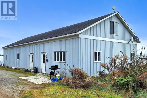 Side exterior view of a light blue agricultural building with windows and doors. - 19654 Mccowan Road, East Gwillimbury