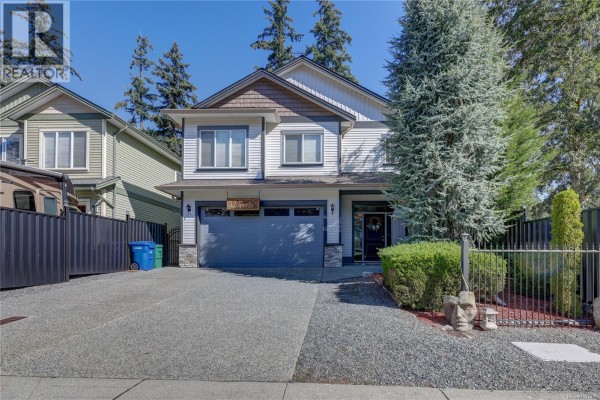 Close-up of the front door with a wreath and a grey garage door. - 1966 Camas Rd, Nanaimo
