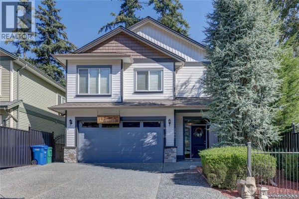Front entrance with a dark grey door, decorative wreath, and a small storage shed. - 1966 Camas Rd, Nanaimo