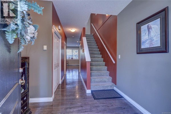 Interior entryway showing a staircase with grey carpet and red walls. - 1966 Camas Rd, Nanaimo