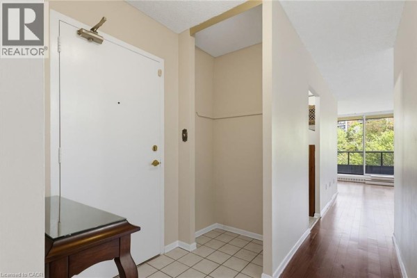 Interior view of an apartment entrance with a white door and tiled floor. - 1966 Main Street W Unit# 503, Hamilton