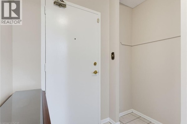 Interior of an apartment hallway with cream-colored walls and a white door. - 1966 Main Street W Unit# 503, Hamilton