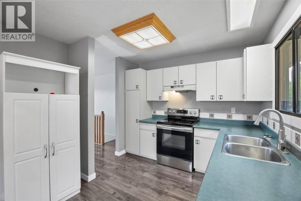 Kitchen with white cabinets, stainless steel appliances, and a teal countertop. - 1967 Harrison Way, Kamloops