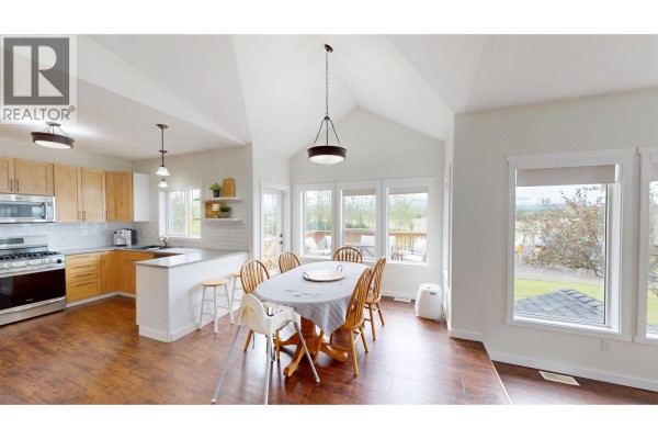 Open concept dining and kitchen area with light wood cabinets, stainless steel appliances, and a large dining table. - 1969 Goold Road, Houston