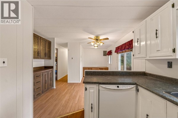 View from the kitchen into the living and dining area with wood-look flooring. - 197 Dauphin Avenue Unit# 207, Penticton