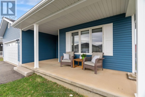 View of the covered porch with white columns, blue siding, and two chairs. - 197 Lake Breeze Drive, Ashfield Colborne Wawanosh