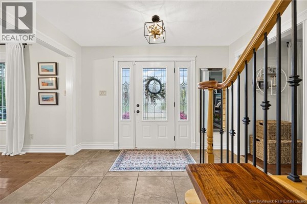 Interior view of the foyer looking towards the front door with tiled floor and ornate chandelier. - 197 Mailhot Avenue, Moncton