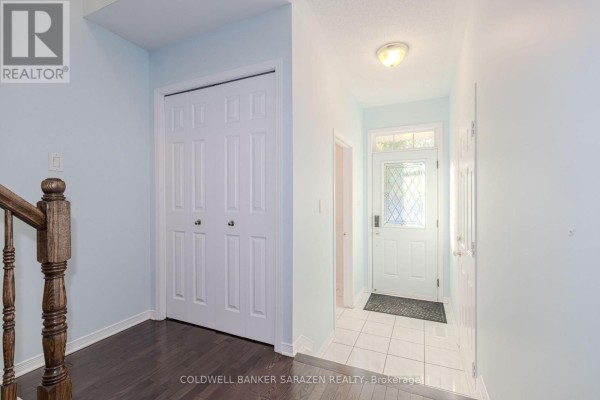 View from inside the townhouse looking towards the front entrance and a wooden staircase. - 197 Portrush Avenue, Ottawa