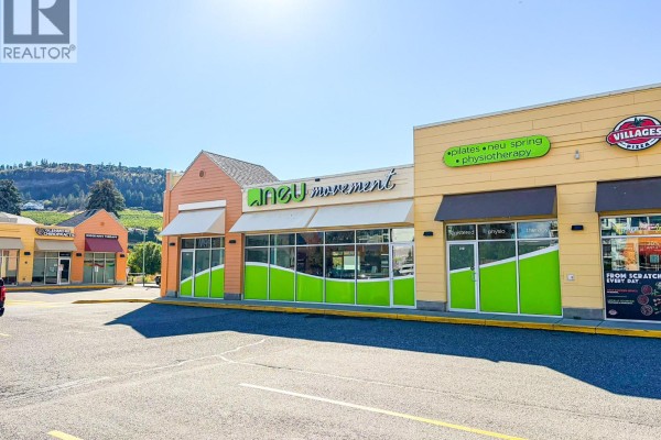 Front exterior view of a commercial building with colorful graphics and mountain backdrop. - 1974 Kane Road Unit# 310, Kelowna