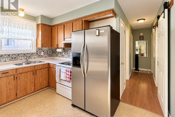 Kitchen with wood cabinets, white countertops, stainless steel fridge, and tile backsplash. - 1976 Royal Crescent, London East