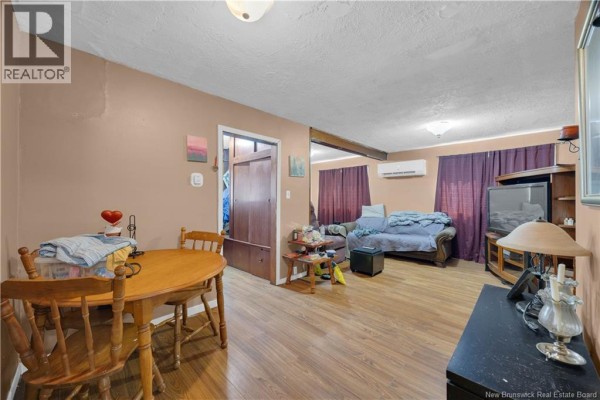 Living and dining area with a wooden table and chairs, a sofa, and purple curtains. - 1979 Westfield Road, Saint John