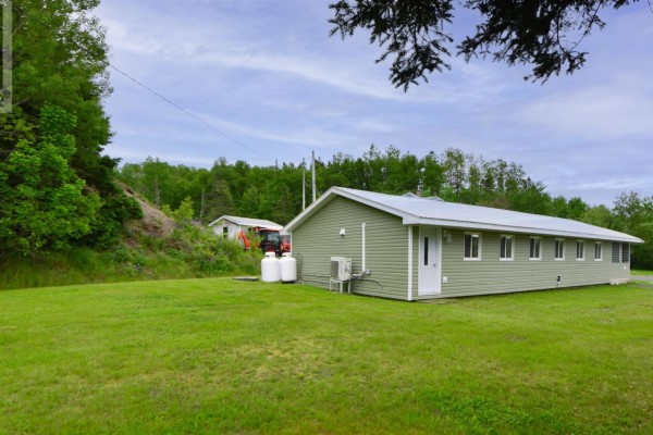 Rear view of the green building showing two large propane tanks and an outdoor air conditioning unit. - 1980 Highway 7, North Lochaber