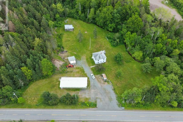 Elevated aerial view of the property showing the main house, the green building, and smaller structures on a grassy lot. - 1980 Highway 7, North Lochaber