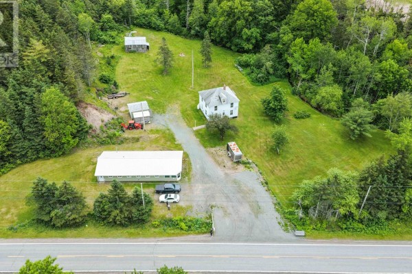 Aerial view of the residential property featuring a white house, a green commercial building, and surrounding landscape. - 1980 Highway 7, North Lochaber