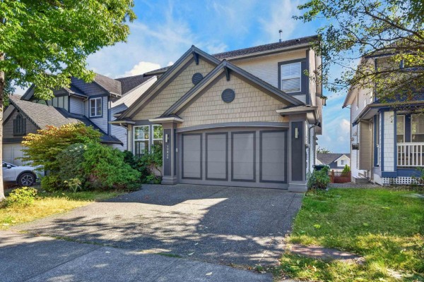 Side exterior view of a two-story house with a grey and beige facade and a double garage. - 19846 69a Avenue, Langley