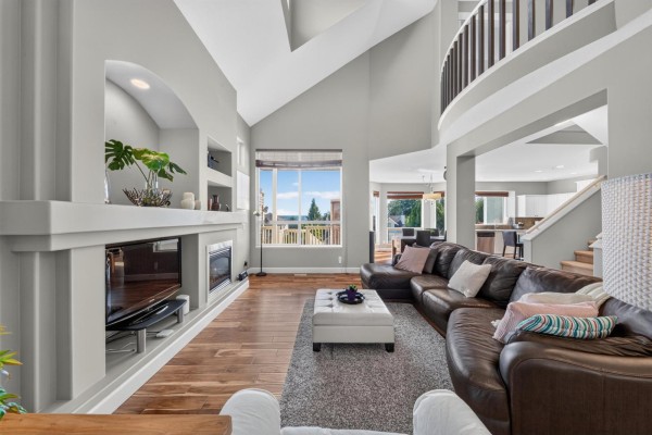 Living room with vaulted ceilings, a fireplace, a large sectional sofa, and wood floors. - 19846 69a Avenue, Langley