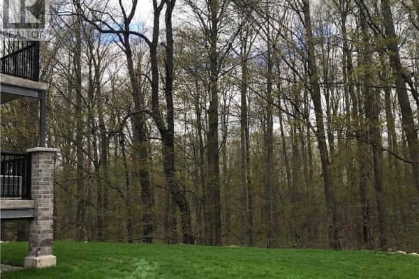 View of a wooded area with green grass in the foreground. - 1989 Ottawa Street S Unit# 28d, Kitchener