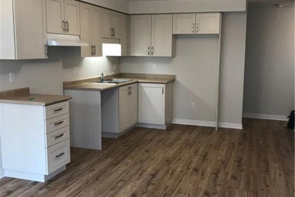A bright kitchen with light wood laminate flooring, light grey cabinets, and stainless steel sink. - 1989 Ottawa Street S Unit# 28d, Kitchener