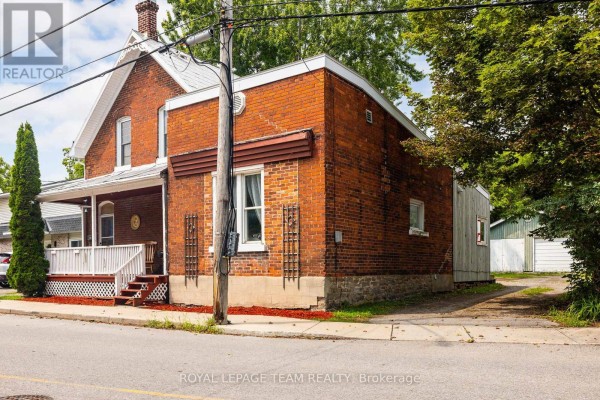 Side view of red brick house with a wooden addition and stone foundation. - 199-201 William Street, Carleton Place