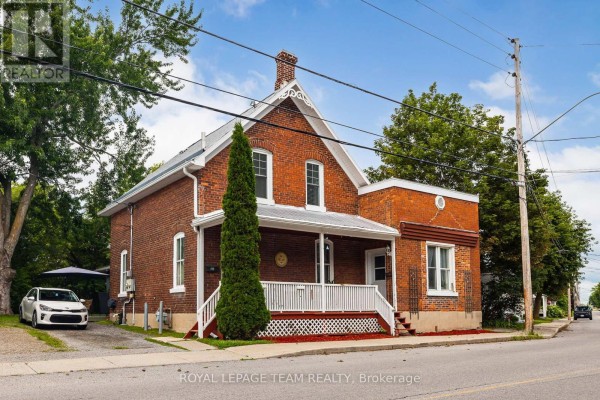 Three-quarter view of a two-story red brick house with trees and a driveway. - 199-201 William Street, Carleton Place