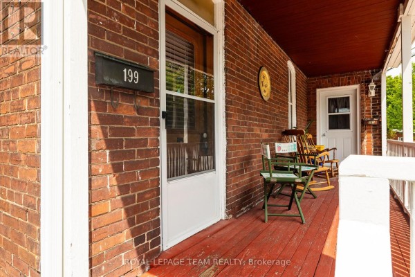 Close-up of a red brick house porch with rocking chairs and the number 199. - 199-201 William Street, Carleton Place