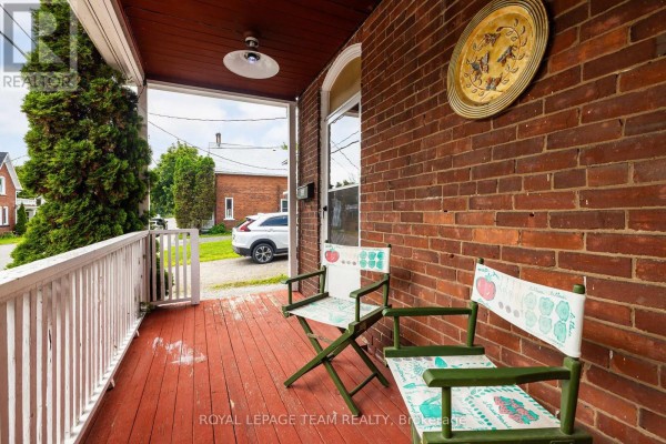 Porch view showing two chairs, brick wall, and a view of the street. - 199-201 William Street, Carleton Place
