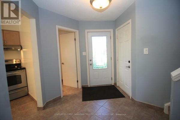 Interior view of a house foyer with light blue walls, tile floors, and several doors. - 199 Emerald Road, London South