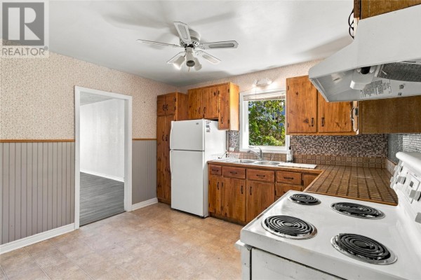 Kitchen with wooden cabinets, a white refrigerator and stove, and a window overlooking greenery. - 199 Freshwater Road, St  John S