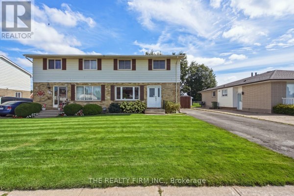 Exterior view of two semi-detached homes with green lawns and cloudy blue sky. - 199 Highview Drive, St  Thomas