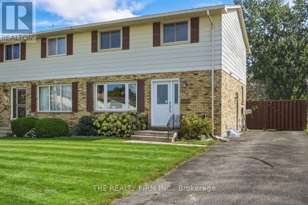 Side view of a beige and brick semi-detached house showing driveway and fence. - 199 Highview Drive, St  Thomas