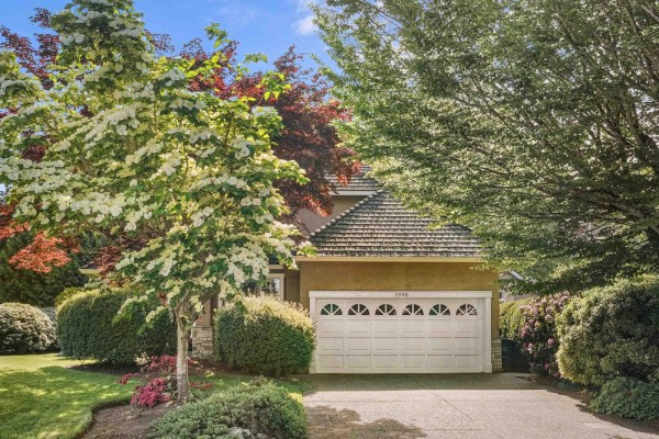 Two-car garage door with arched windows, set within a beige house facade and landscaping. - 1990 Ocean Wind Drive, Surrey