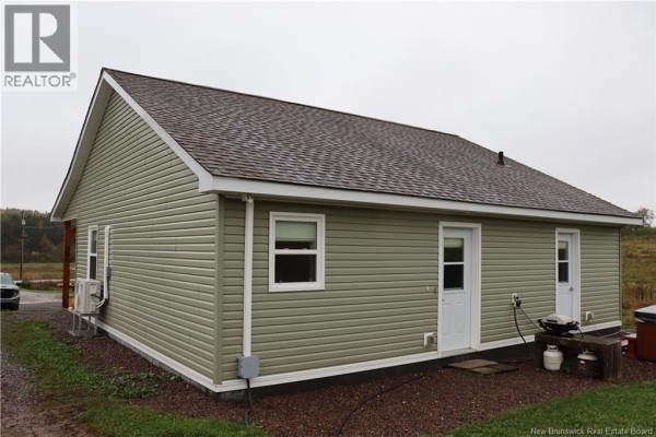 A light green vinyl-sided house with a dark shingled roof and two side doors. - 1991 121 Route, Norton