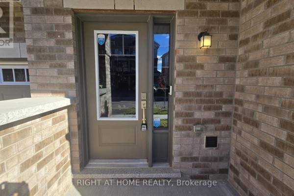Front door entrance of a townhouse with a glass pane door and brick exterior. - 1992 Cameron Lott Crescent, Oshawa