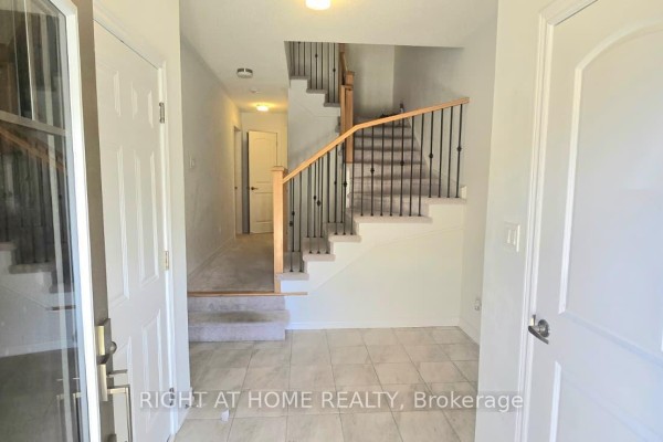 Foyer with tiled floor, carpeted stairs, and hallway with doors. - 1992 Cameron Lott Crescent, Oshawa