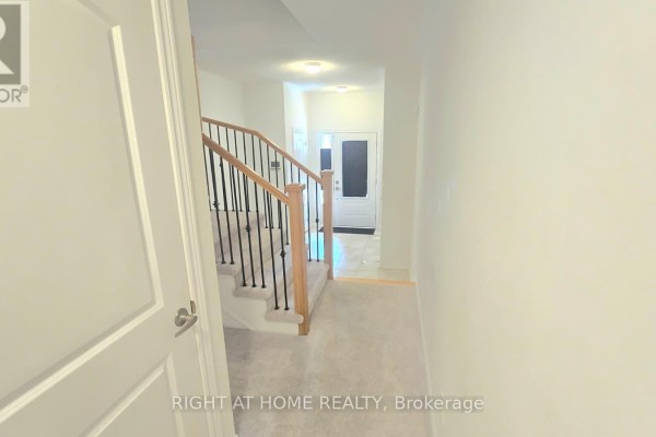 Hallway view showing carpeted stairs, doors, and entrance to foyer. - 1992 Cameron Lott Crescent, Oshawa