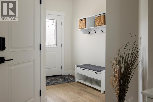 Interior entryway with white walls, a bench with storage, and a hallway leading to the front door. - 1999 15 Avenue Unit# 19, Vernon