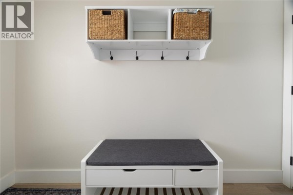 White wall with a shelf with baskets and hooks above a storage bench. - 1999 15 Avenue Unit# 19, Vernon