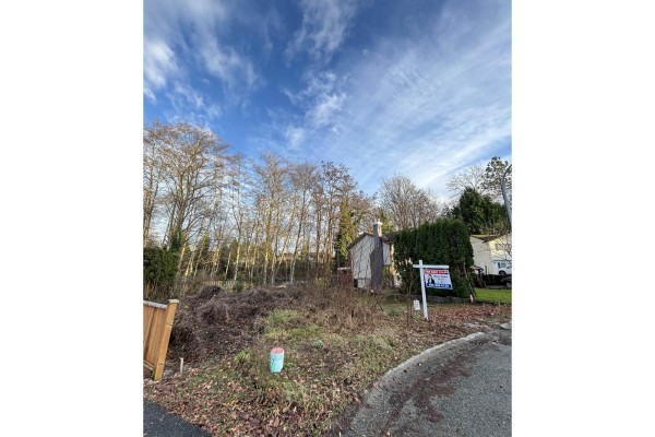 Vacant lot with a small shed, for sale sign, and surrounding trees. - 19995 50a Avenue, Langley