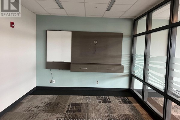 Office with a mounted media console, whiteboard, blue-green walls, and glass partition. - 1b - 1329 Gardiners Road, Kingston