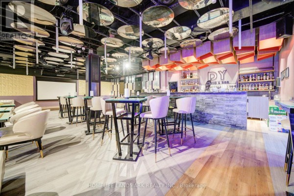 Bar area with a stone facade, bar stools, bottles on shelves, and tables in the foreground. - 1b - 2901 Kennedy Road, Toronto