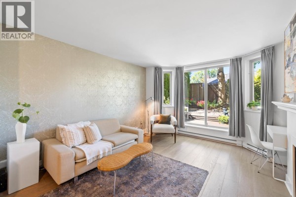 Living and dining room with beige sofa, white table, and wooden credenza. - 1b 2775 Fir Street, Vancouver