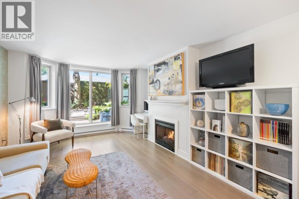 Living room with sofa, table, credenza, and shelving against white walls. - 1b 2775 Fir Street, Vancouver