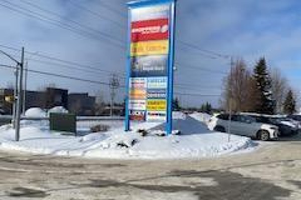 Tall vertical sign with multiple colored business names in a snowy landscape. - 1b1 - 649 Yonge Street, Barrie