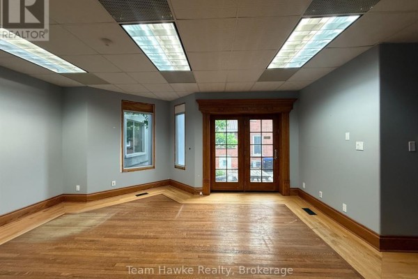 Interior room with hardwood floors, grey walls, wood trim, and double glass doors. - 1e - 361 King Street, Midland