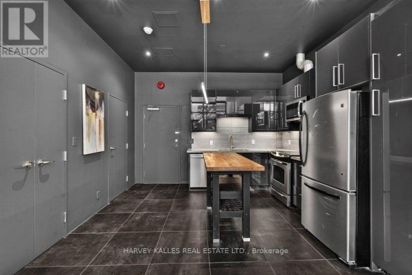 Kitchen with grey cabinets, stainless steel appliances, a wooden island, and tiled floor. - 1e - 86 Gerrard Street E, Toronto