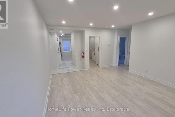 Open concept living space with light wood-look flooring and white walls. - 1u - 35 Wellington Street, Brantford